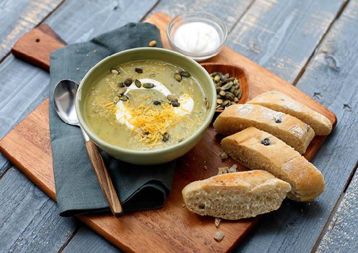 Romige aardappel-courgettesoep met pompoenpitten en oude kaas