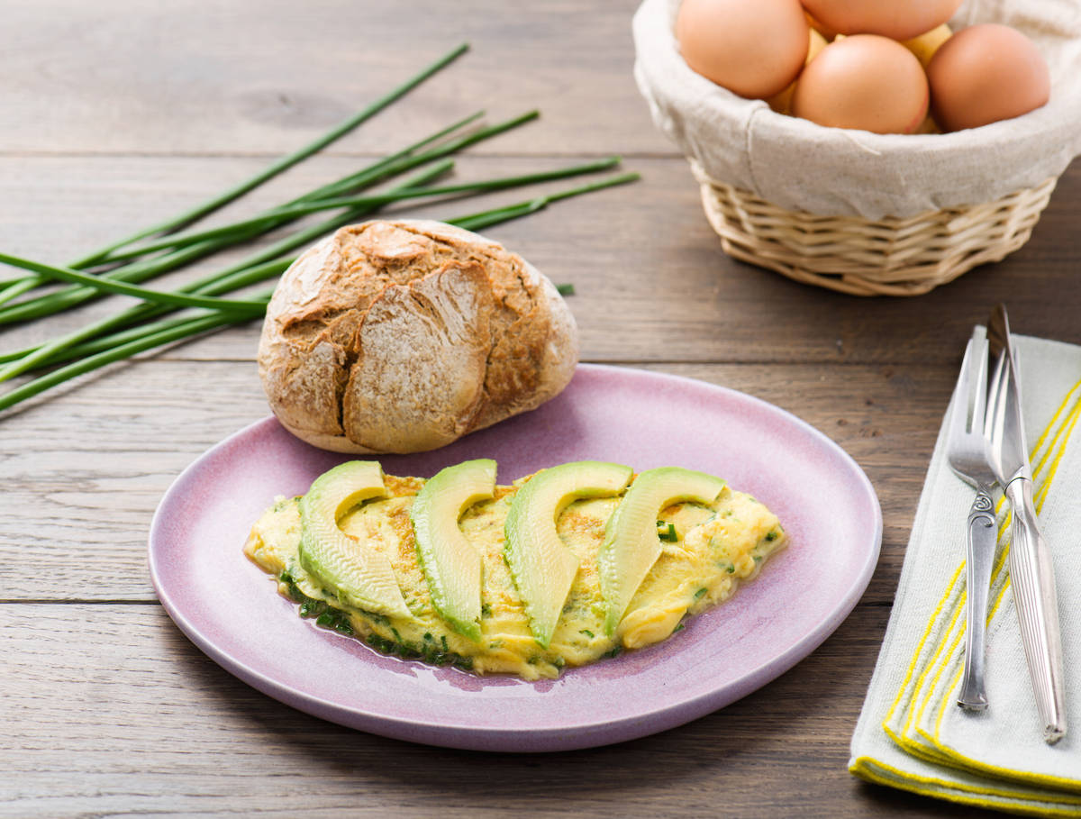Omelet met avocado en een bruin rozenbroodje