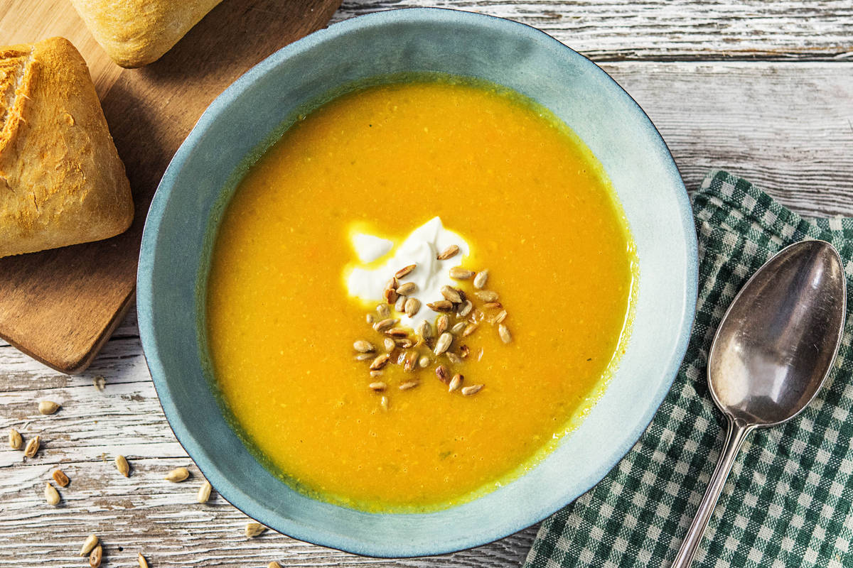 Zoete bataat-wortelsoep en frisse yoghurt met zonnebloempitten en een kurkumabroodje