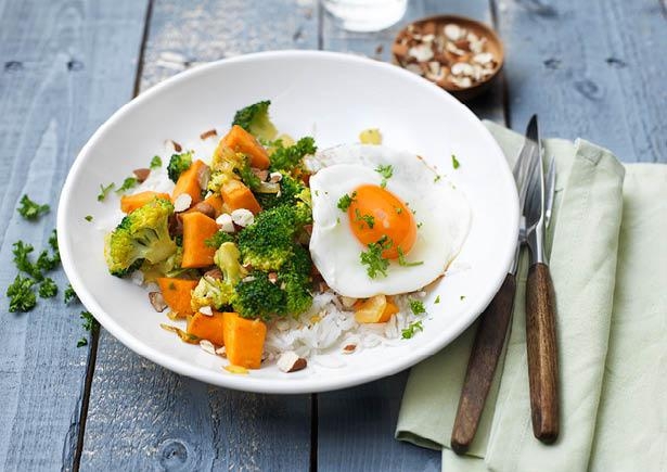 Zoete rijstschotel met broccoli, amandelen en spiegelei