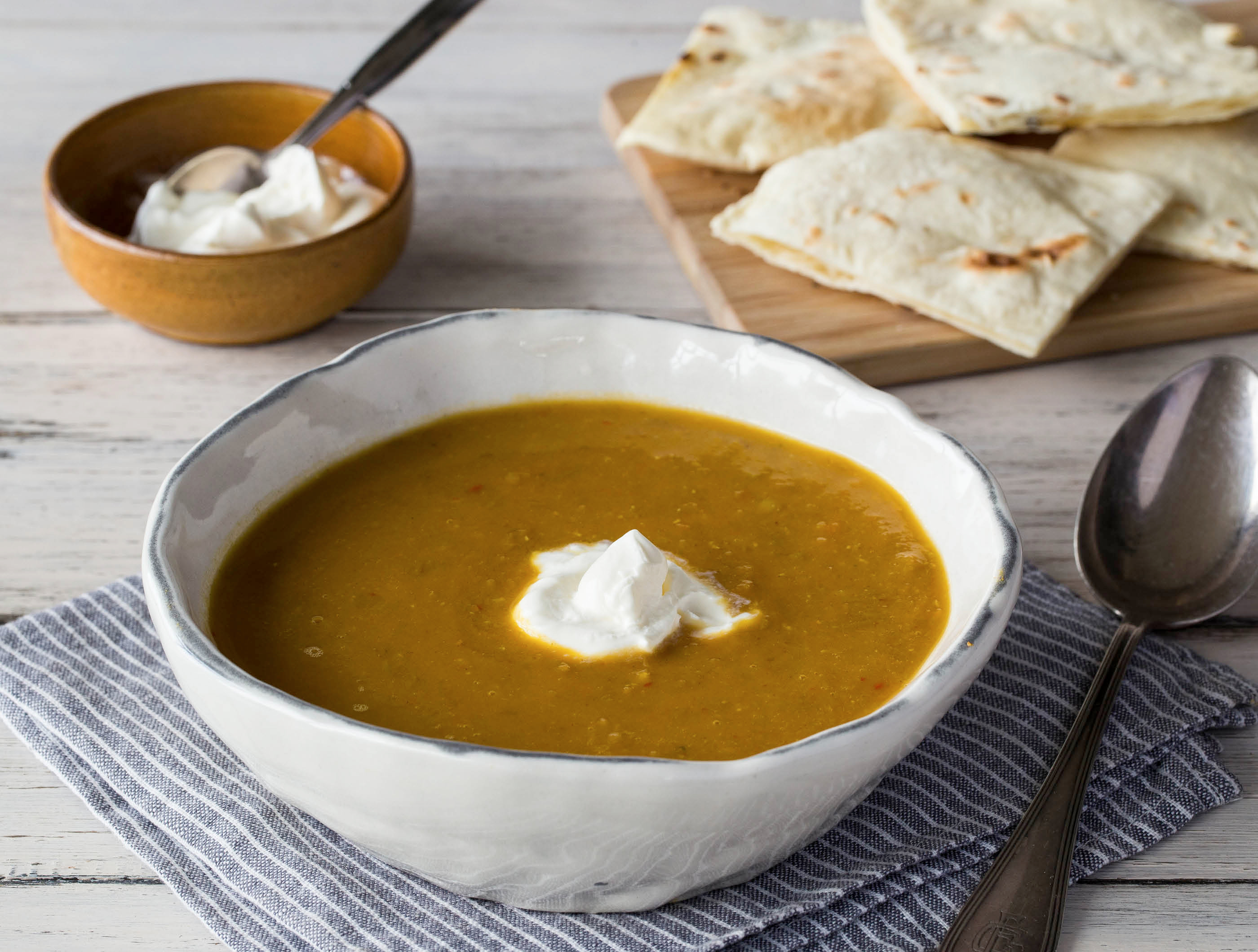 Zoete wortel–linzensoep met crème fraîche en naanbrood