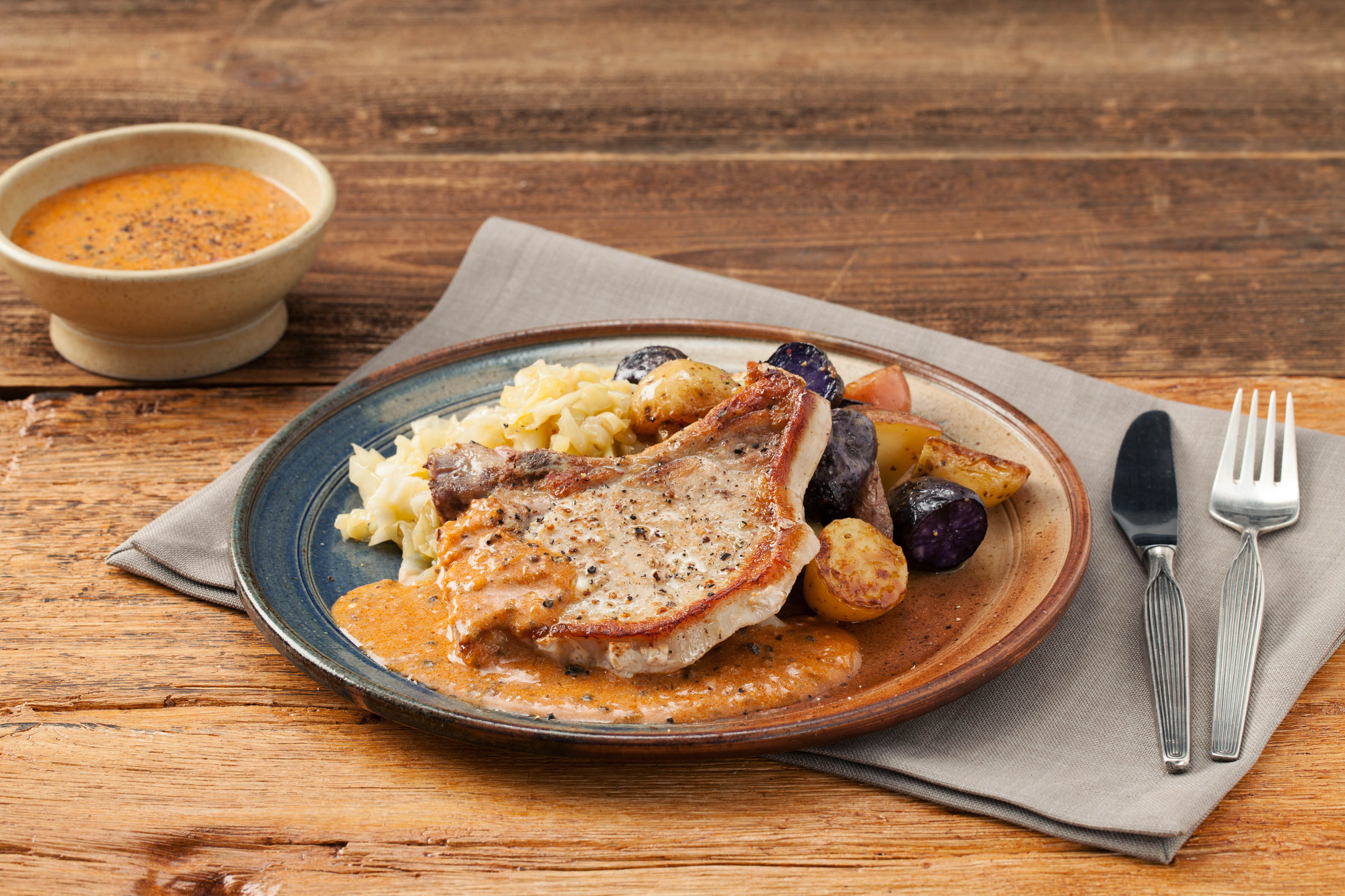 Bone-In Pork Chops with Shallot-Peppercorn Sauce, Butter-Braised Cabbage, and Crispy Potatoes