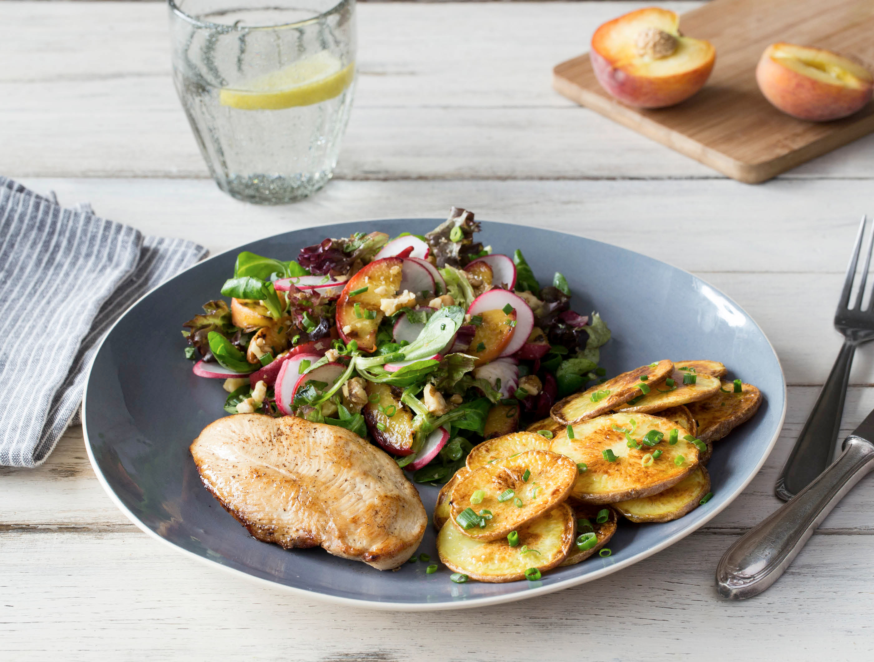 Gebakken kipfilet, ovenaardappelen en salade met gegrilde perzik