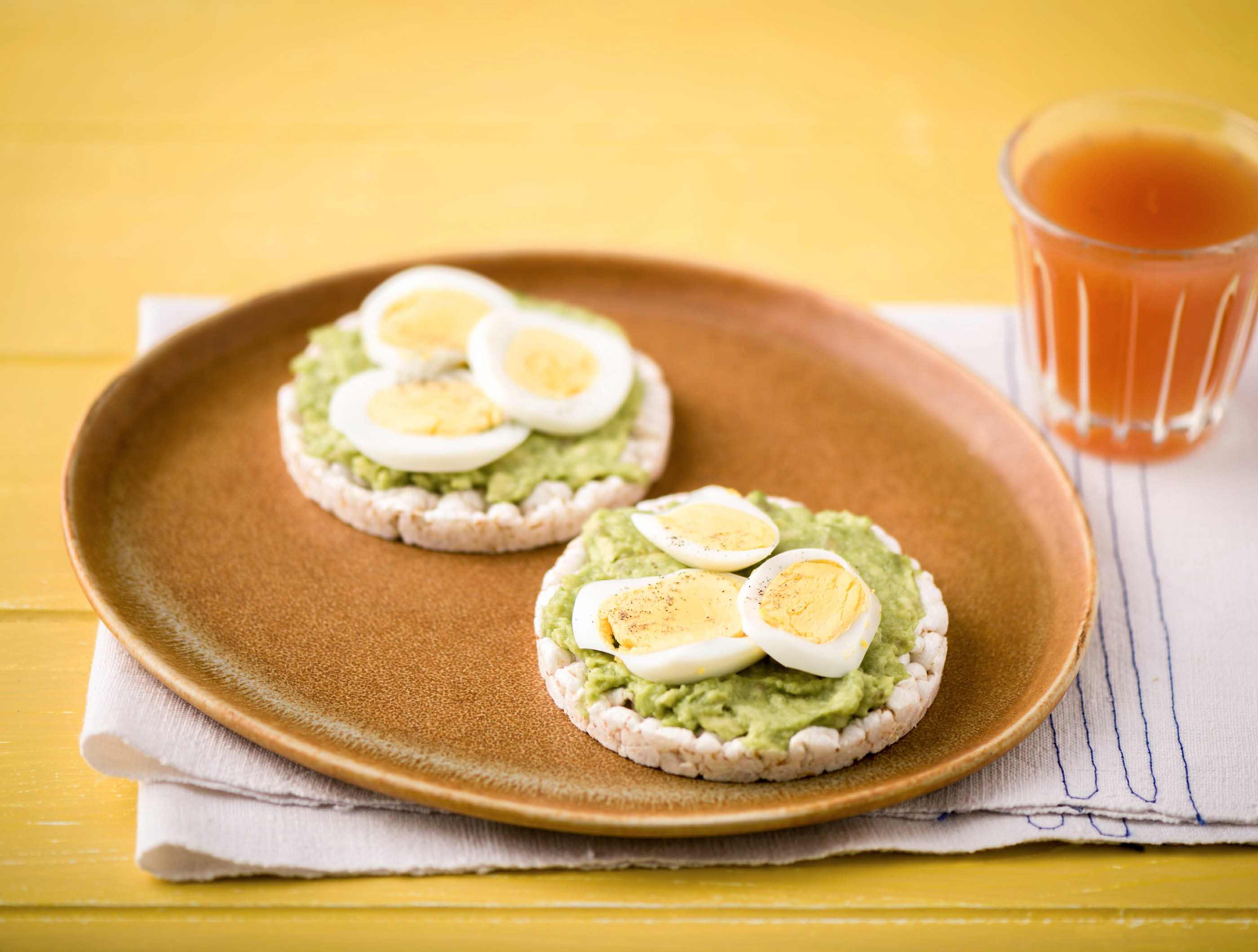 Finse ronde sesamcrackers met avocado, gekookt ei en verse jus d’orange