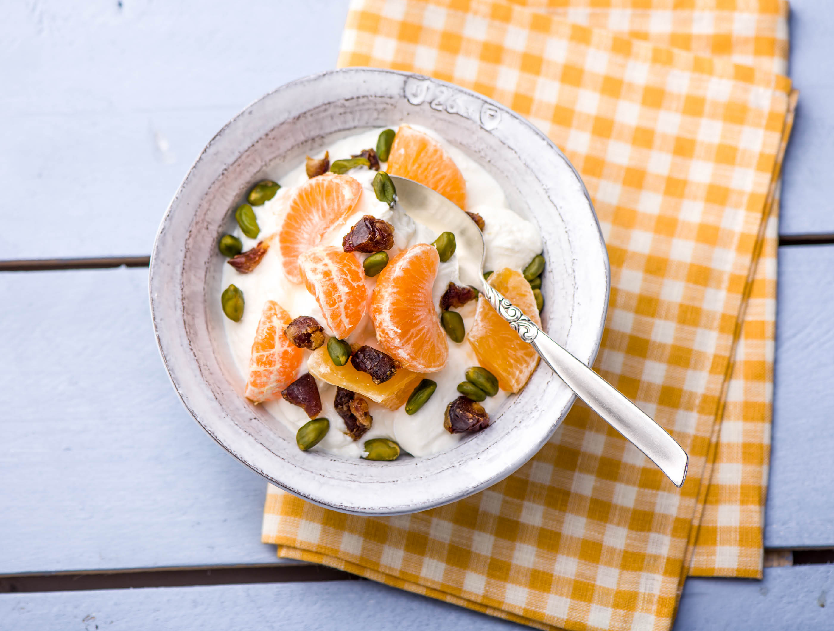 Volle kwark met oranje fruit, pistachenoten en dadels