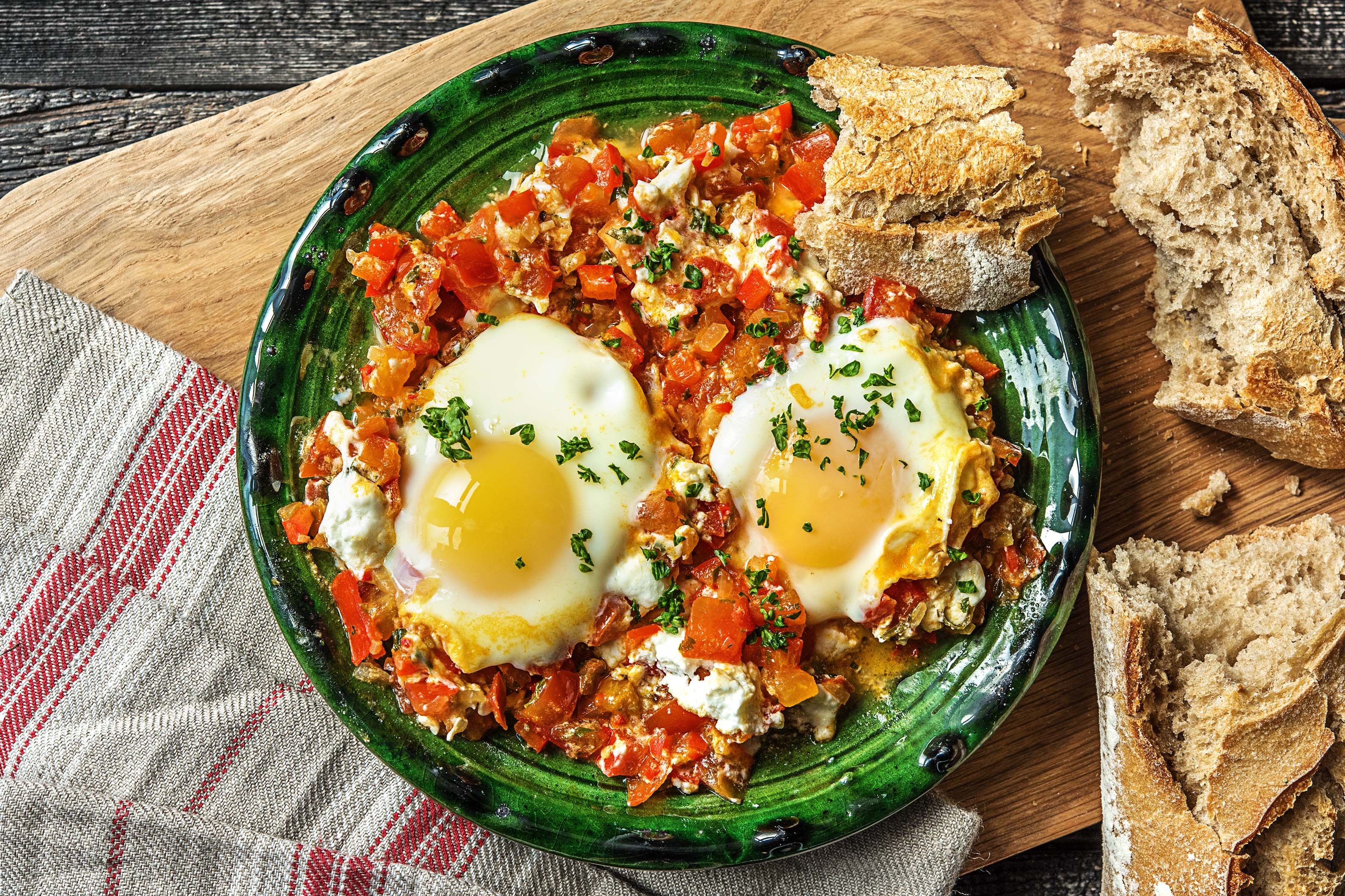 Traditionele shakshuka met ei, geitenkaas en speltbaguette