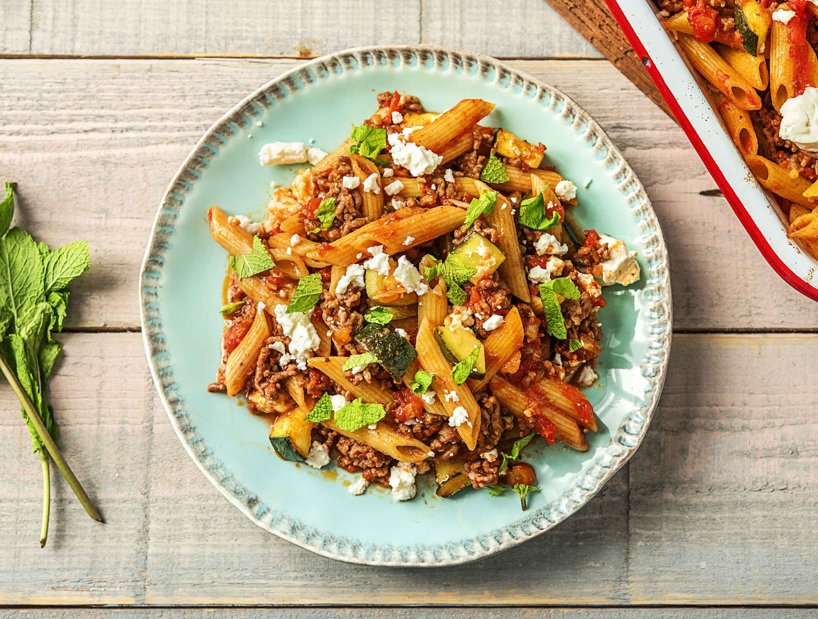 Ovenschotel met kruidig gehakt, penne integrale, courgette, geitenkaas en munt