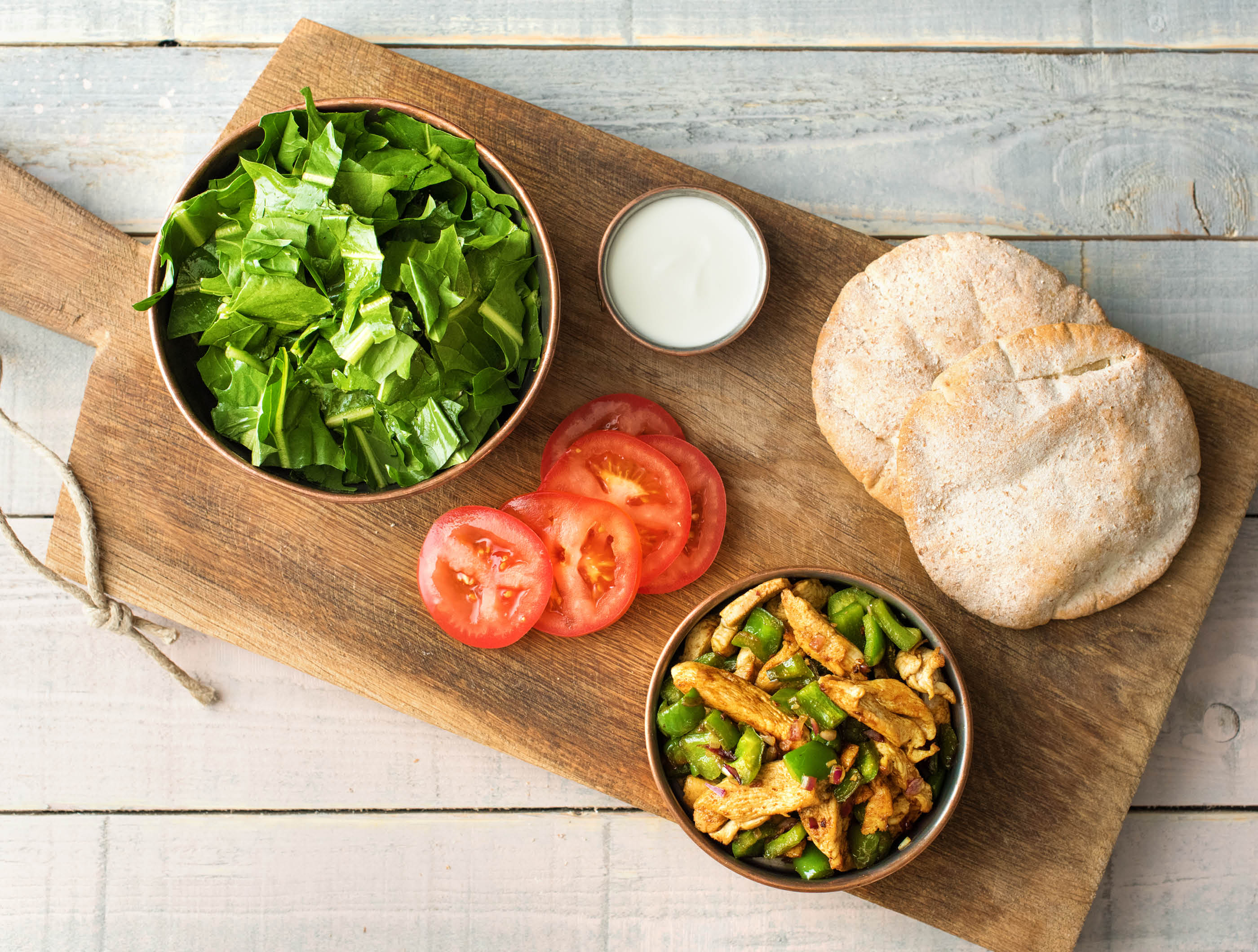 Pains pita complets à l’émincé de poulet accompagnés de yaourt et de salade