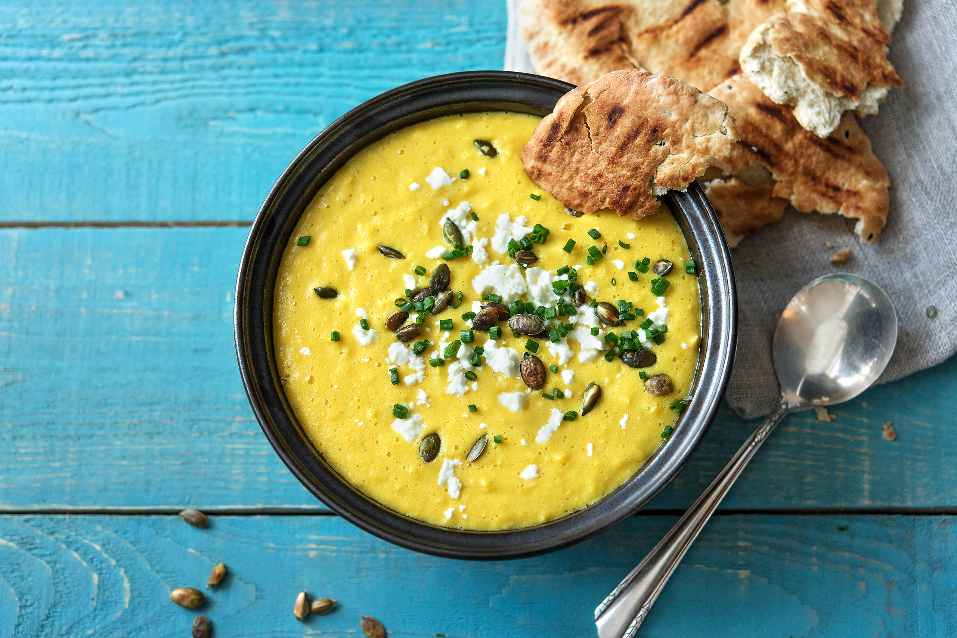 Soupe au poivron jaune et au maïs garnie de feta et de graines de courge