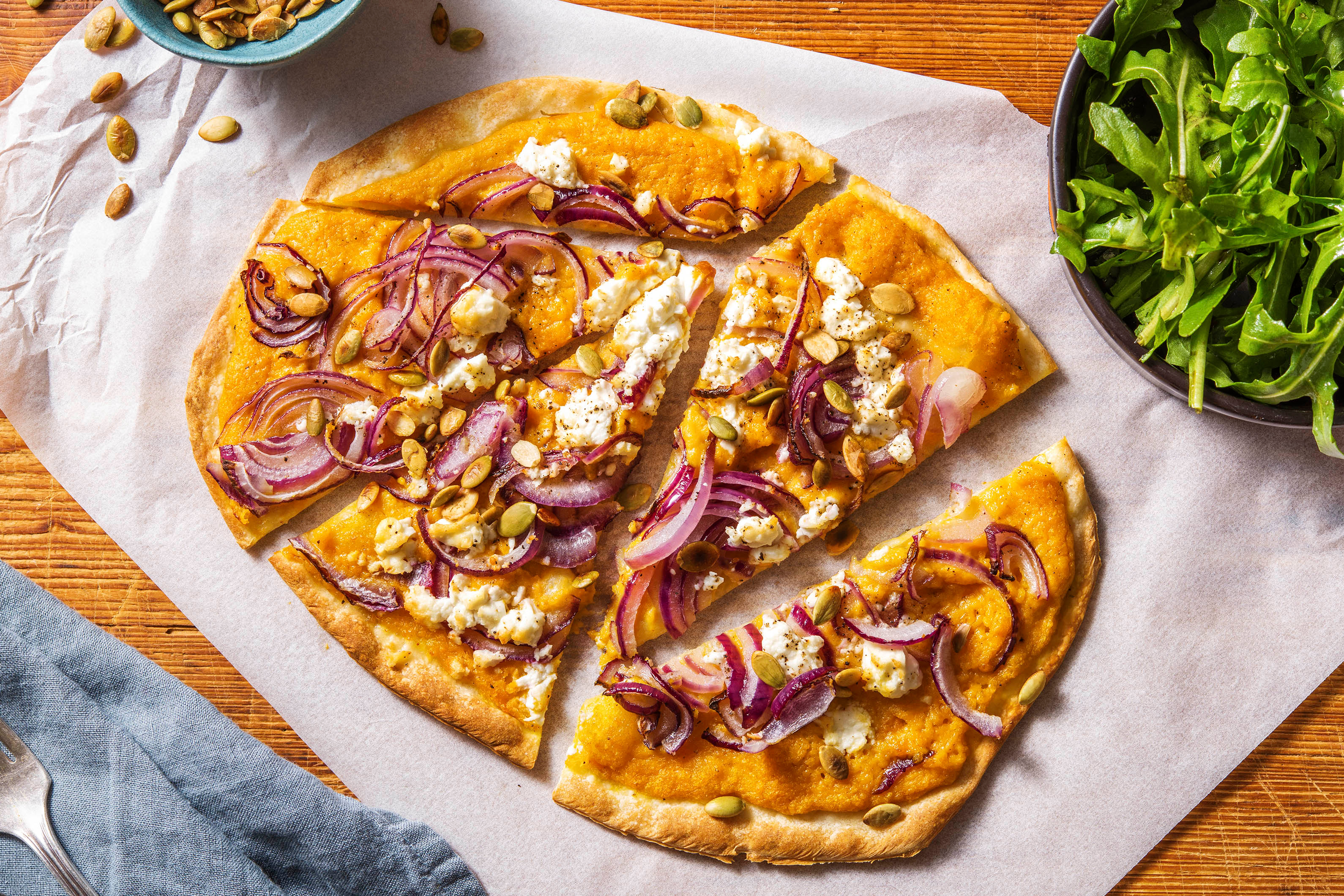 Tarte flambée avec une sauce de potiron à la crème, de la feta et de l'oignon rouge