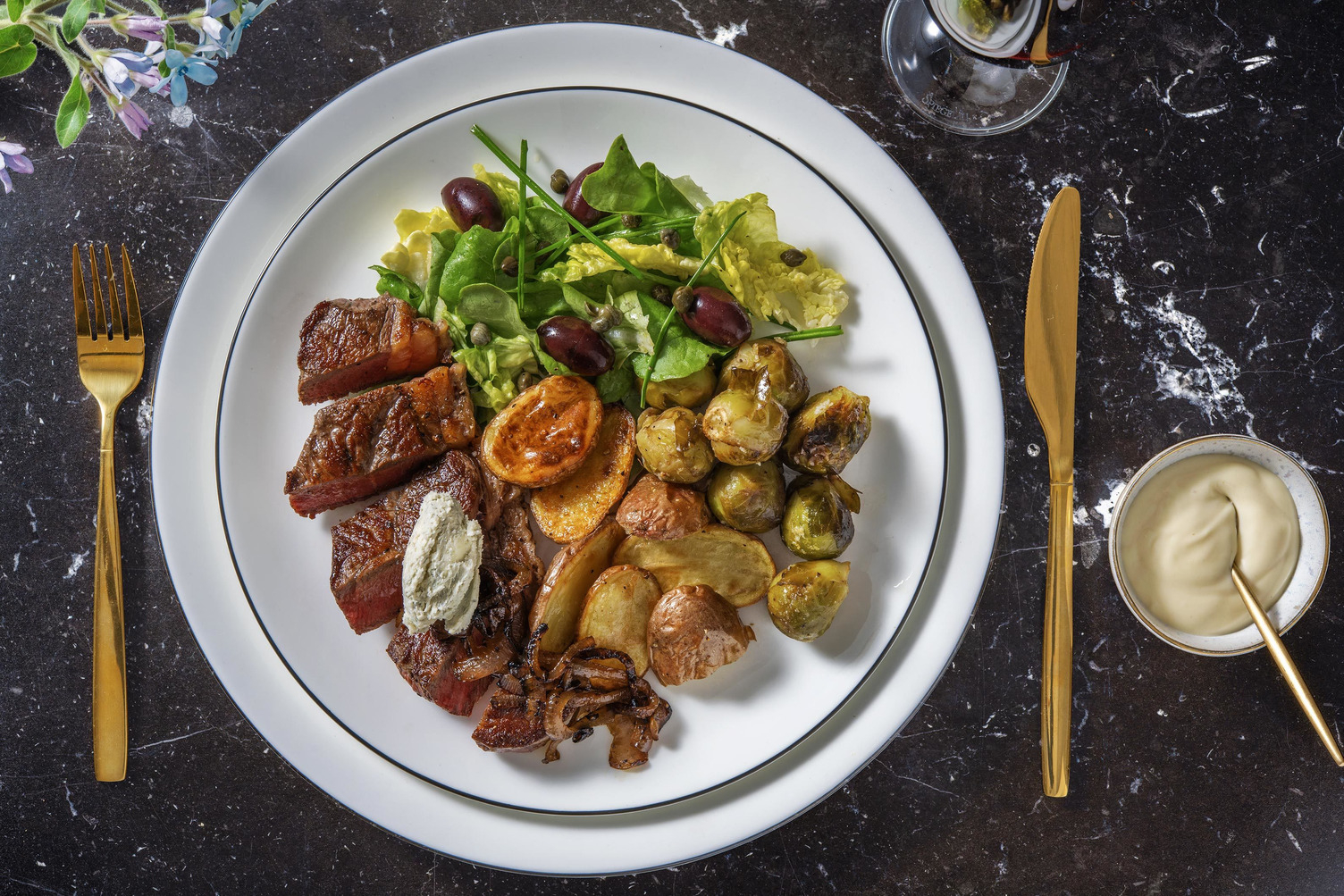 Steak servi avec un beurre au bleu et des oignons rouges caramélisés