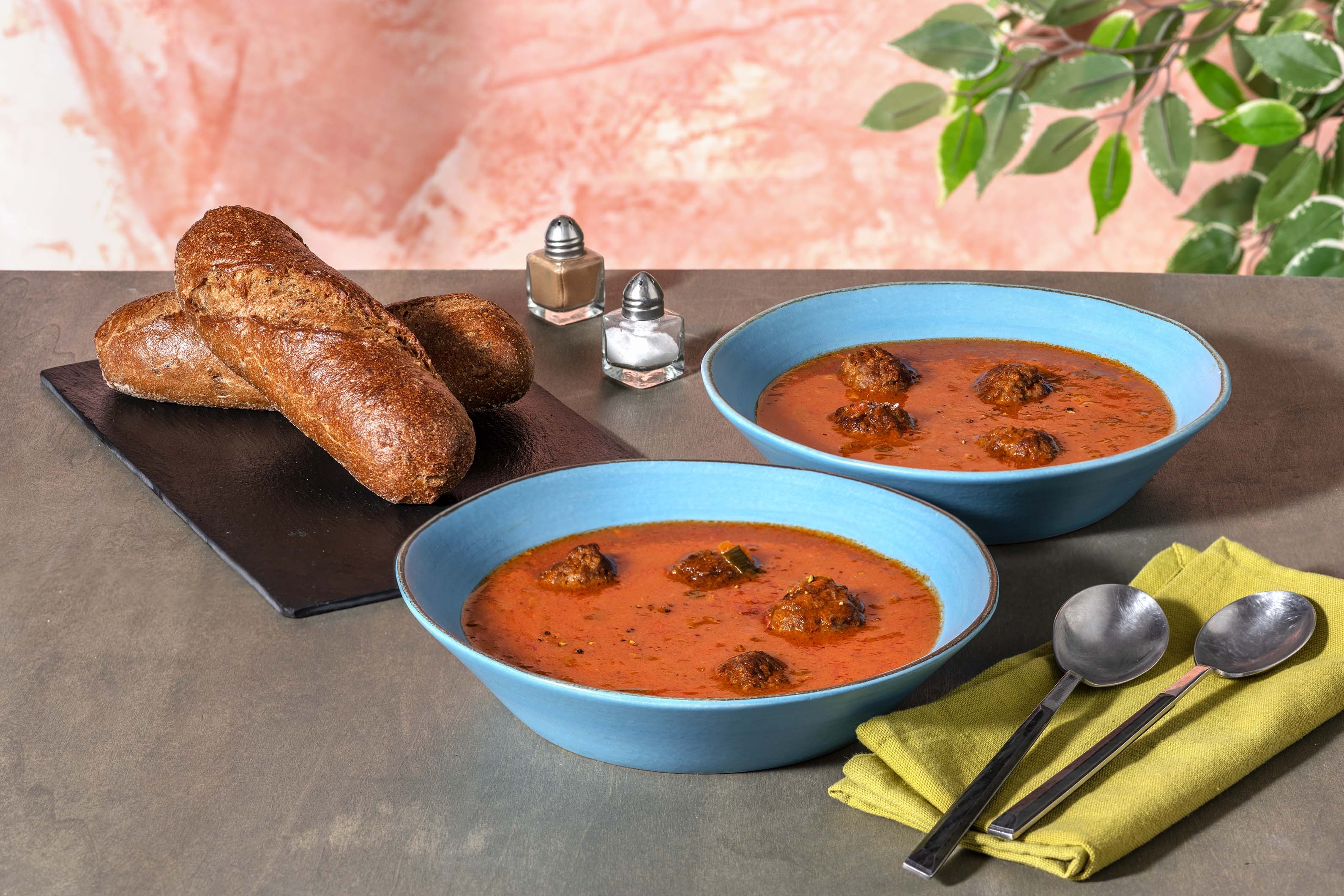 Soupe de tomates et boulettes de viande servie avec un demi-baguette woutkorn