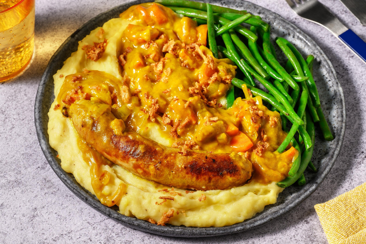 Varkensworst in currysaus met gefrituurde uitjes