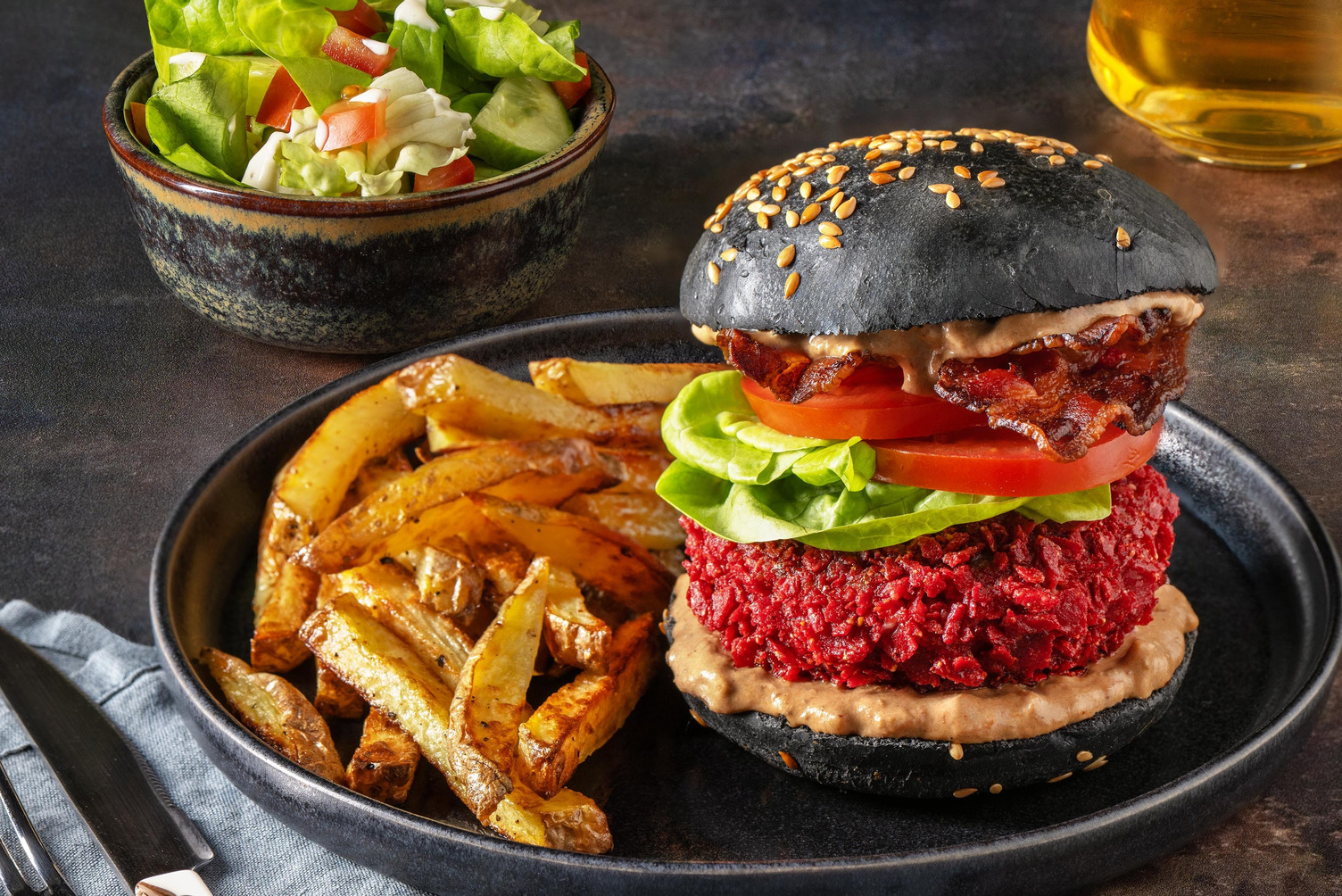 Bacon burger met bietentortillachips op zwart streetfoodbroodje