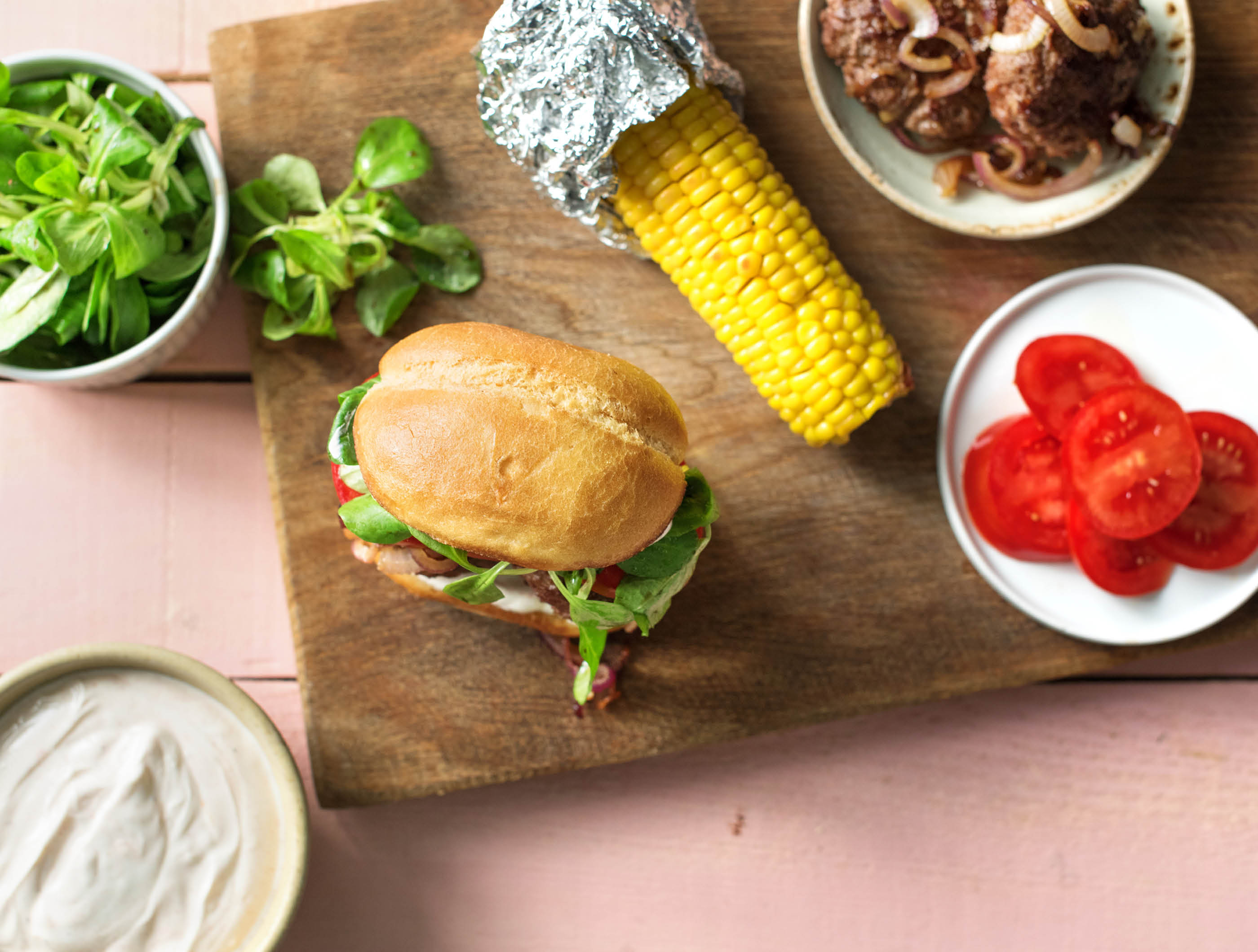 Broodje köfte-runderburger met paprika-yoghurtsaus en maïskolf