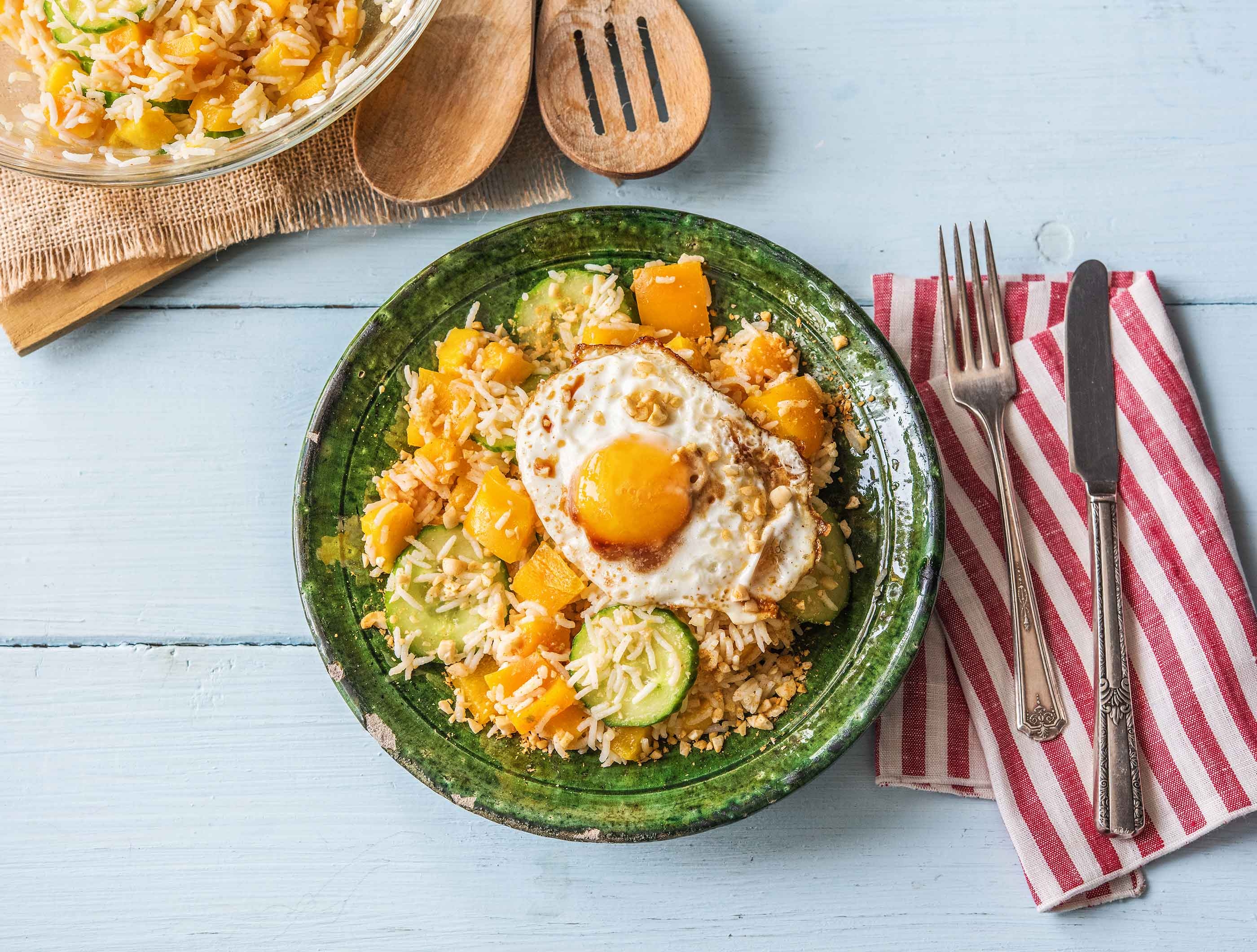 Oosterse rijstsalade met paprika, mango, gekruide notenmix en een spiegelei