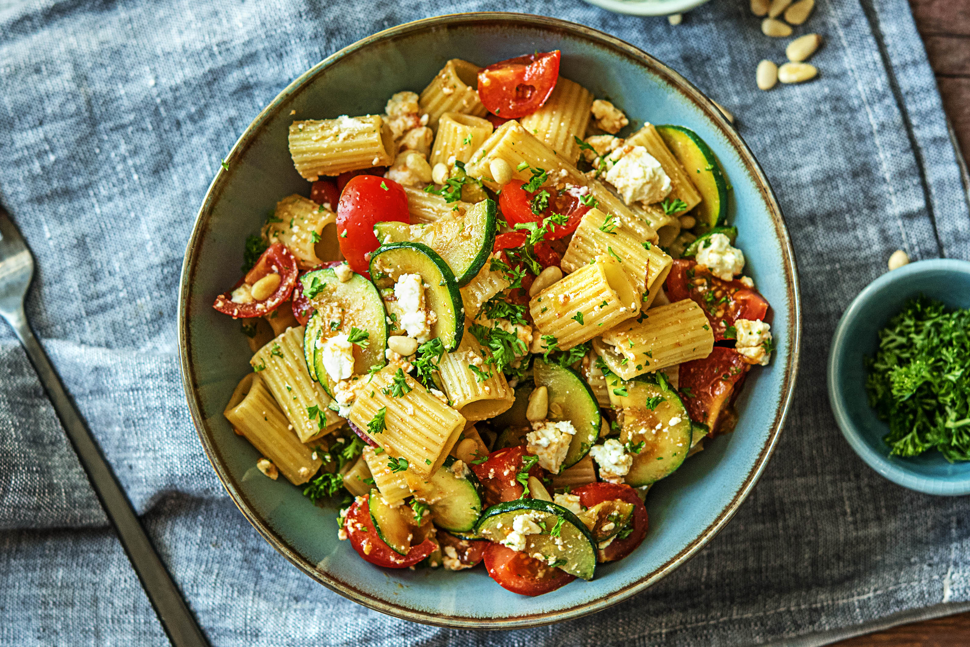 Rigatonisalade met courgette, cherrytomaten, feta en geroosterde pijnboompitten