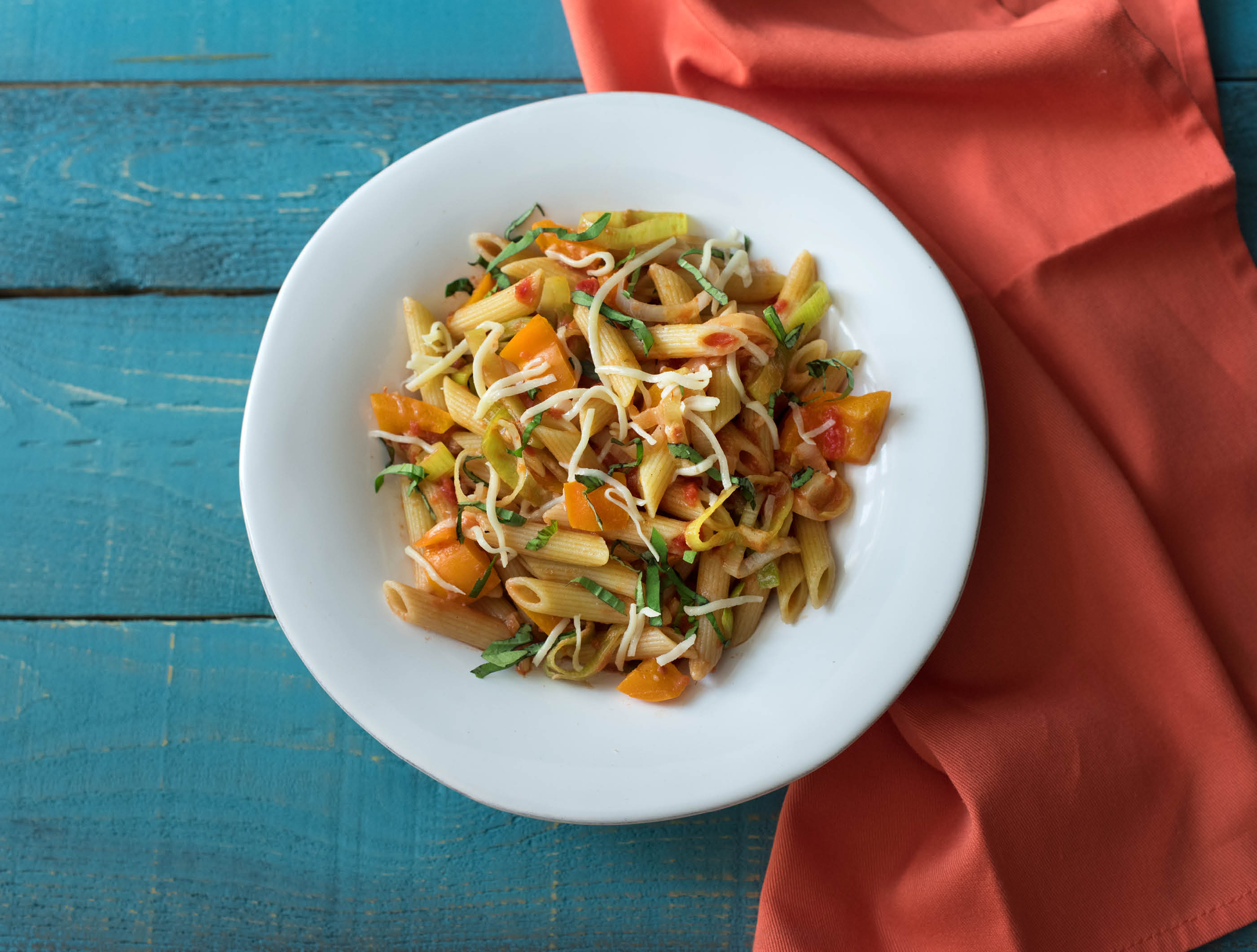 Snelle penne met tomatensaus, oude kaas en basilicum