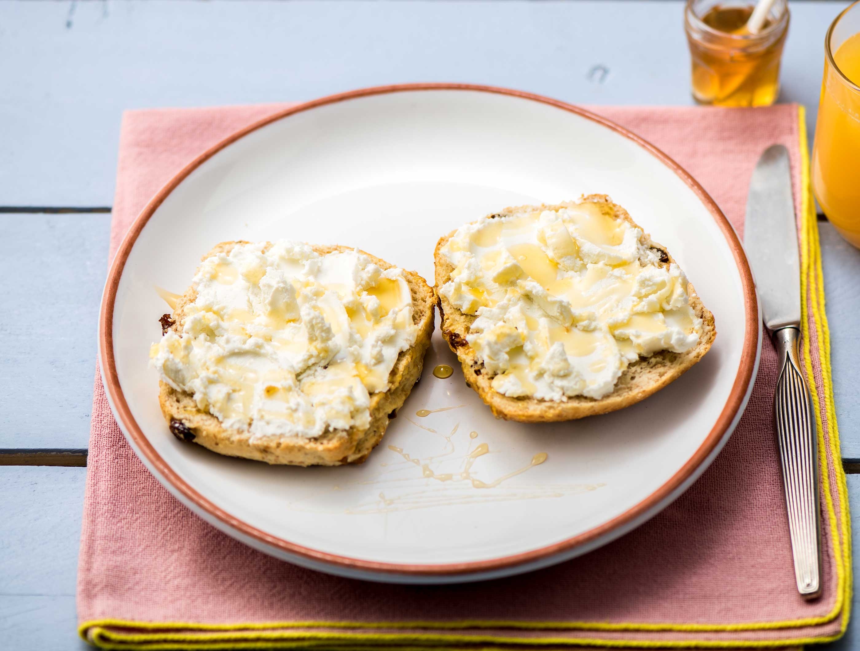 Volkoren rozijnen-notenbroodje met geitenkaas, honing en sinaasappelsap
