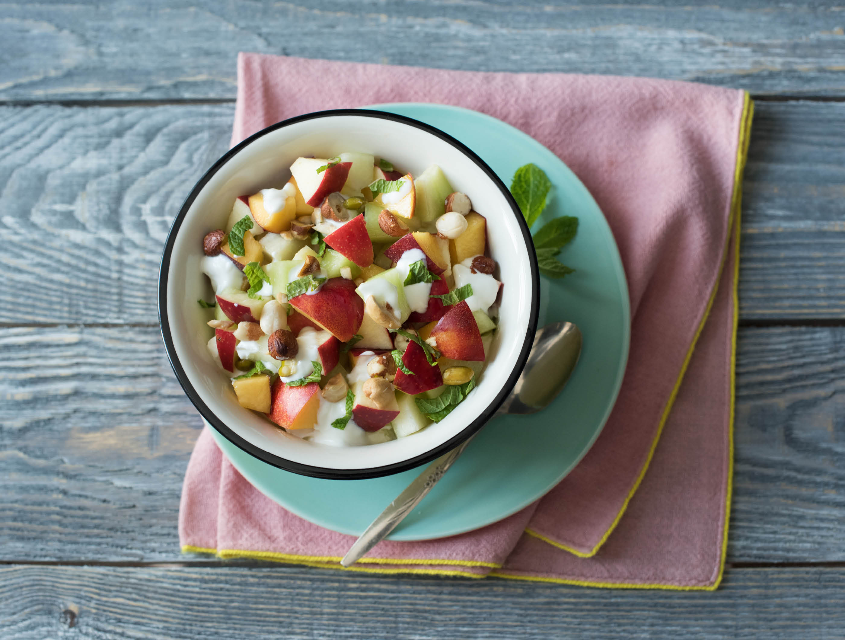 Zomerse fruitsalade met noten, volle kwark en citroenmelisse