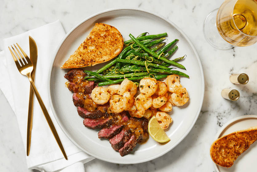 STEAK AU POIVRE with Cheesy Hasselback Potatoes, Creamed Kale, and Shallot-Peppercorn Sauce