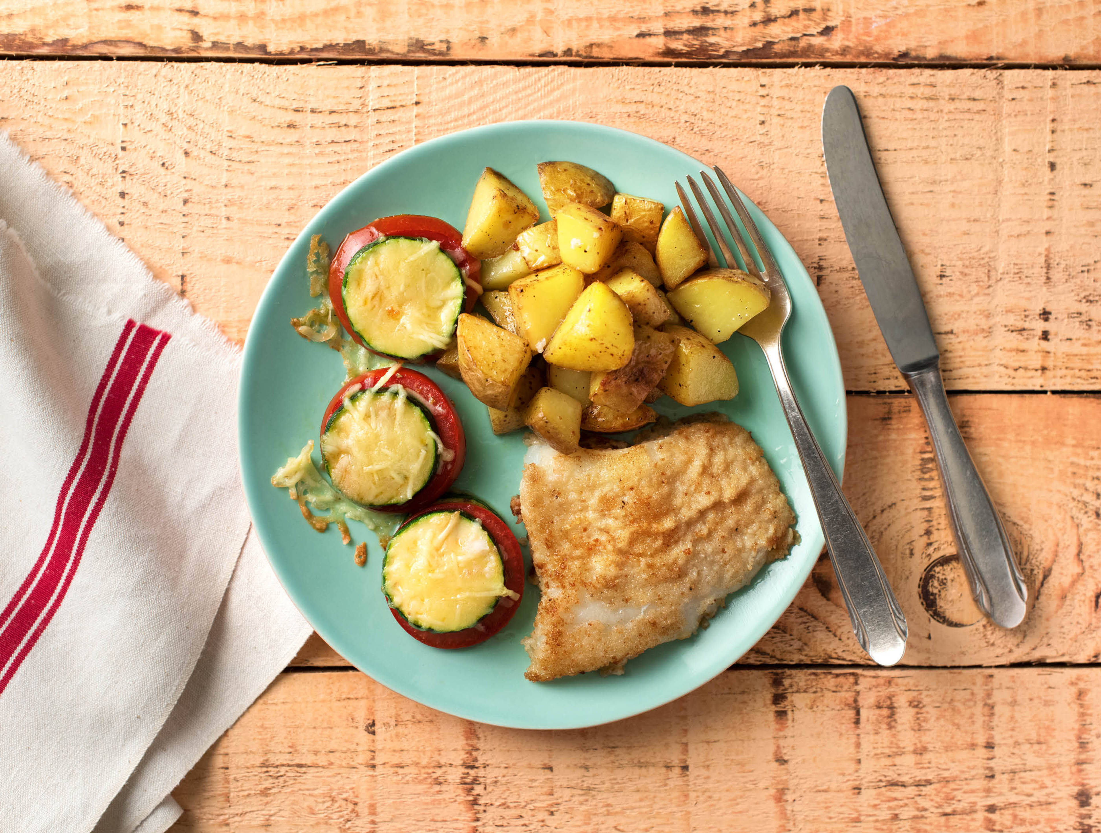 Escalope de poisson, petites tours de légumes et pommes de terre rôties