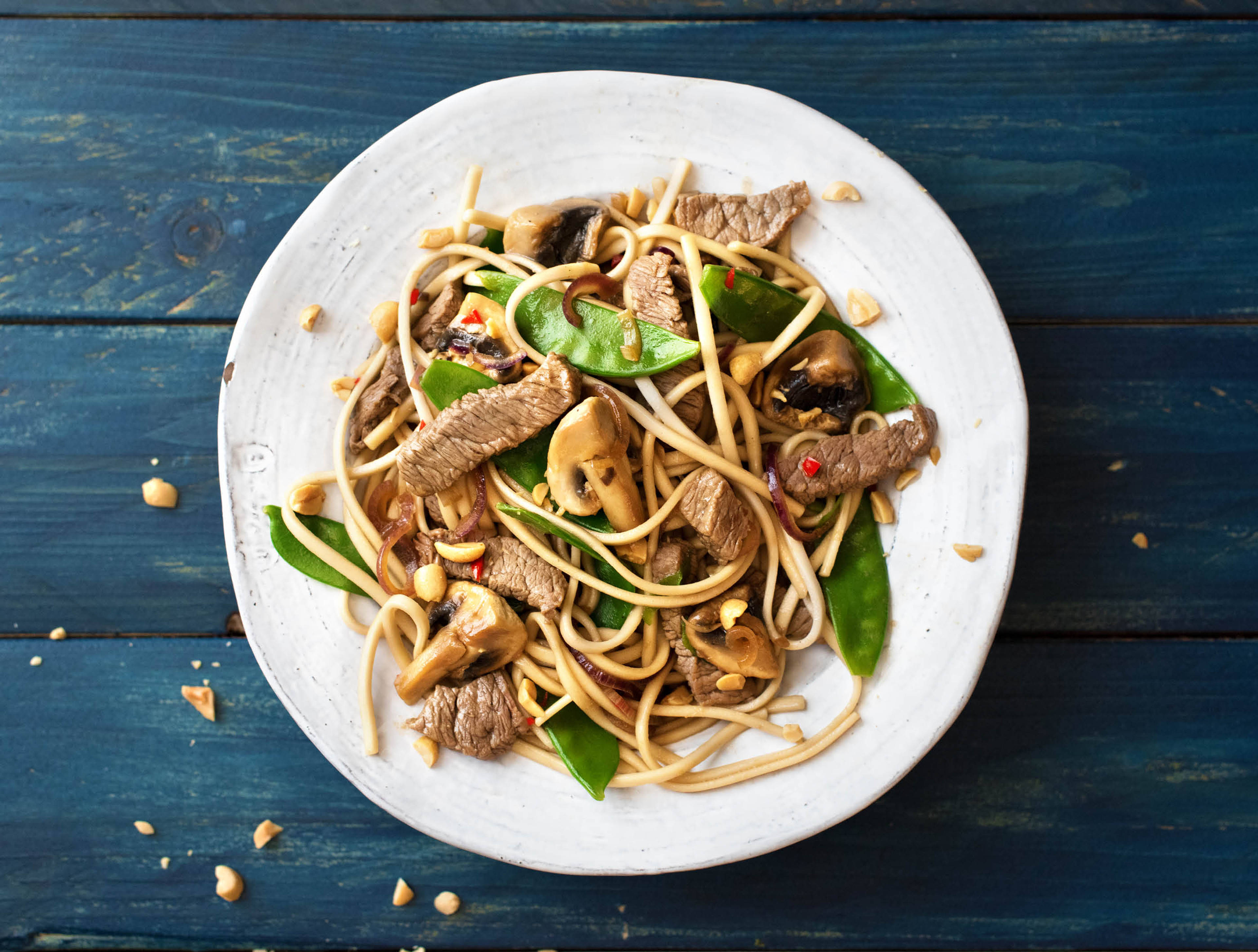 Salade de nouilles chaude avec des lanières de bœuf, pois mange-tout dans une sauce orientale
