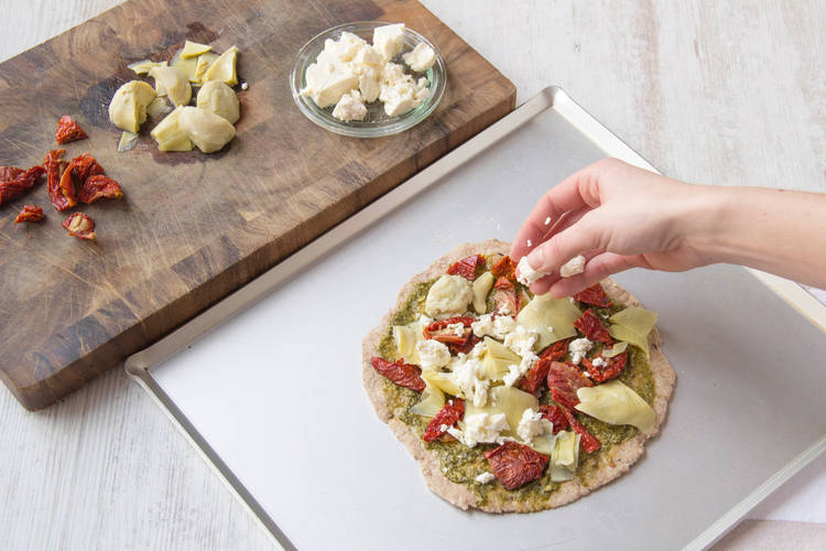 Sprinkle pizza with ingredients