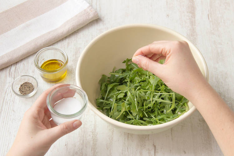 Den Rucola Salat würzen