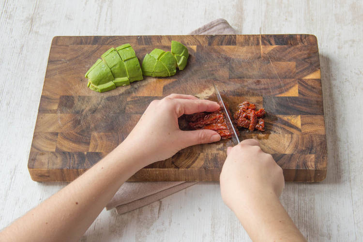 getrocknete Tomaten grob hacken, Avocado in Würfel schneiden