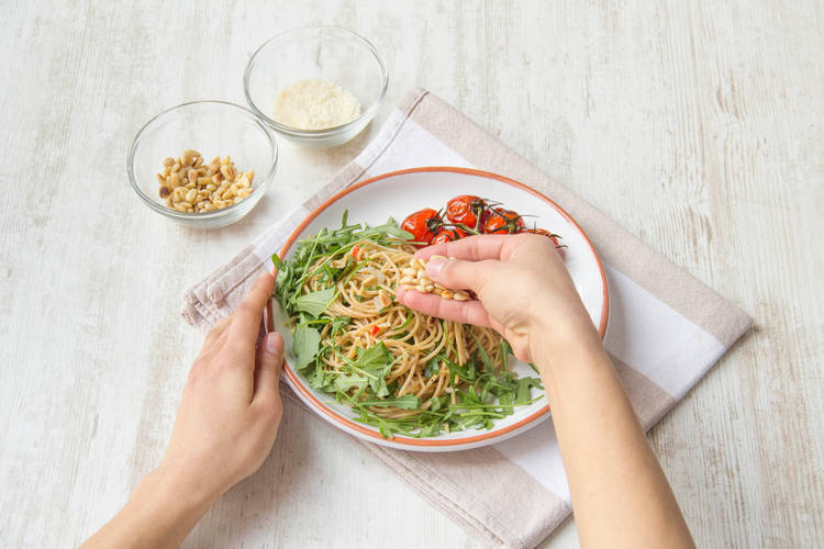 Garneer met de pijnboompitten en overige rucola, basilicum en grana padano