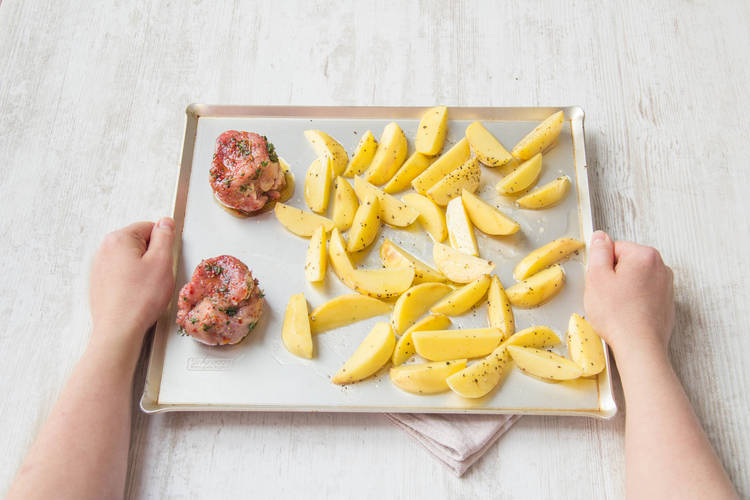 Die marinierten Filets zu den Kartoffeln auf das Backblech legen