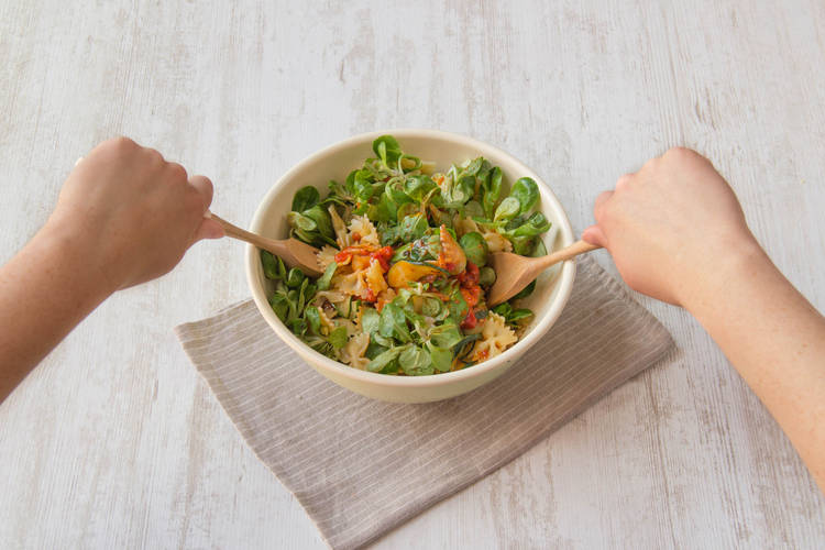 Meng de mesclun met de courgette, farfalle, rode paprikapesto, zwarte balsamicoazijn en overige lenteui