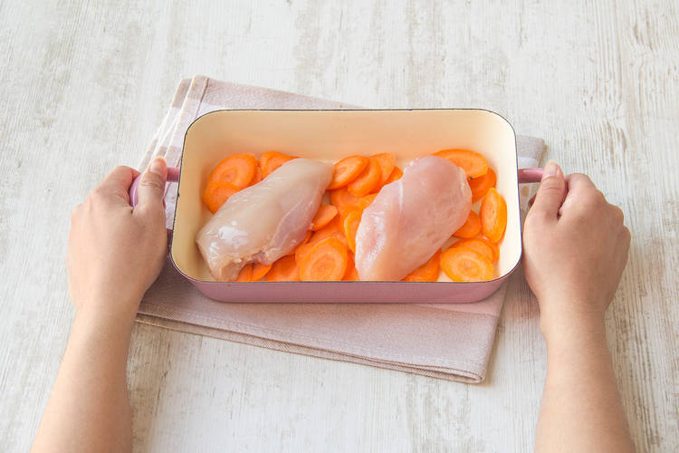 Hähnchenfilets gemeinsam mit den Karotten in einer Auflaufform verteilen