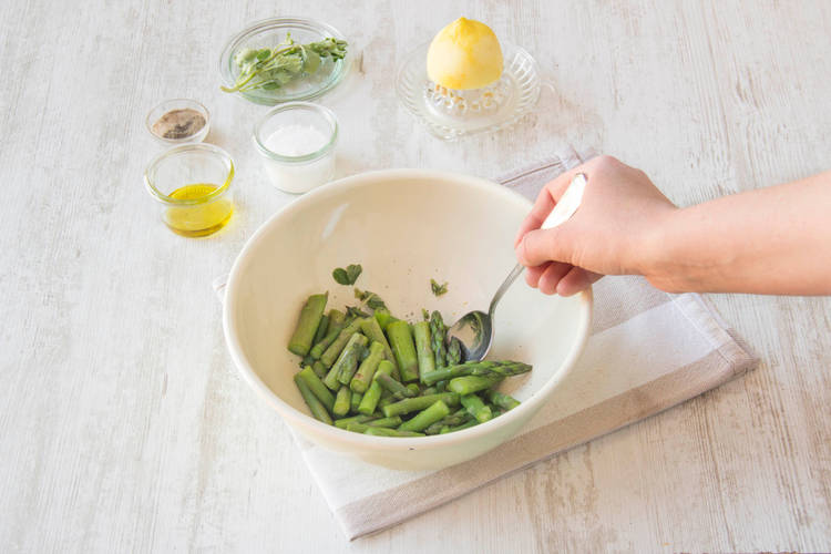 Meng de asperges met de oregano, citroenrasp, olijfolie, peper en zout