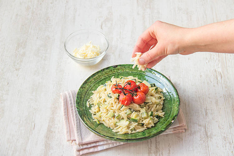 Verdeel de orzo over de borden en garneer met de overige gruyère. Serveer de mini-romatrostomaten op de orzo, aan de tros.