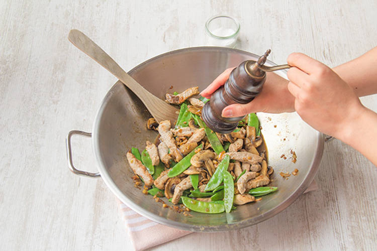 Voeg de varkenshaasreepjes toe en breng op smaak met peper en zout.