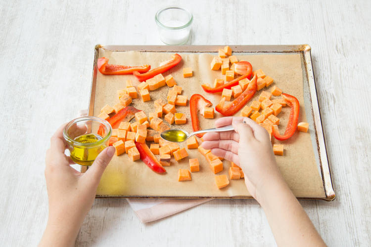 Besprenkel de zoete aardappel en de paprika met de helft van de olijfolie.