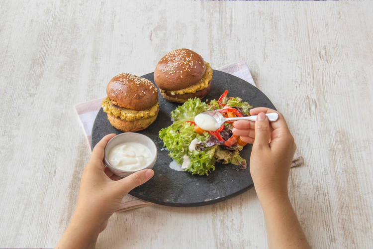 Serveer de burgers met de salade.