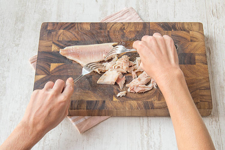 Verdeel de gerookte forel met een vork in kleine stukken.