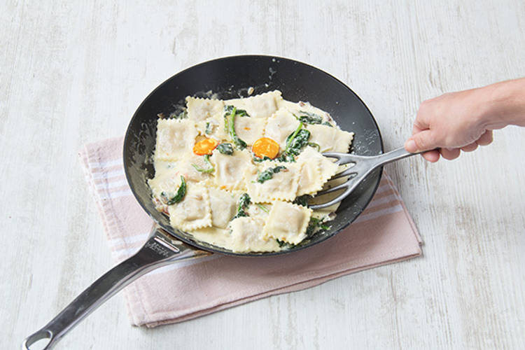 Roer de ravioli door de saus