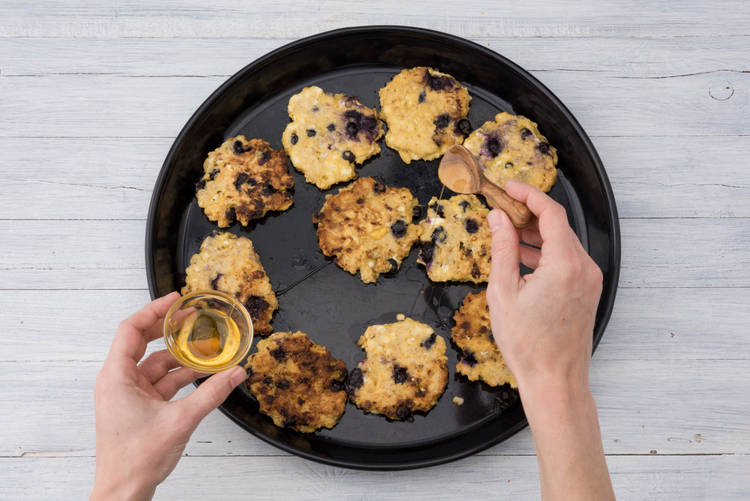Schenk de honing over de pannenkoekjes.