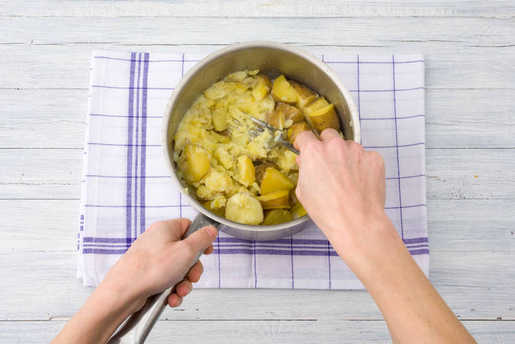 Stamp de aardappelen tot een grove puree.