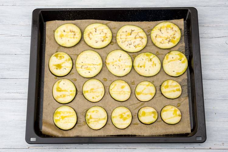 Verdeel de aubergine op een bakplaat met bakpapier en wrijf in met de helft van de olijfolie, peper en zout.