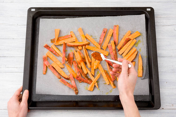 erdeel de frietjes over een bakplaat met bakpapier.