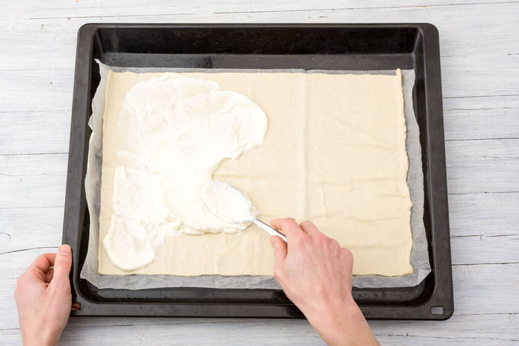 Flammkuchen mit Schmandmischung bestreichen