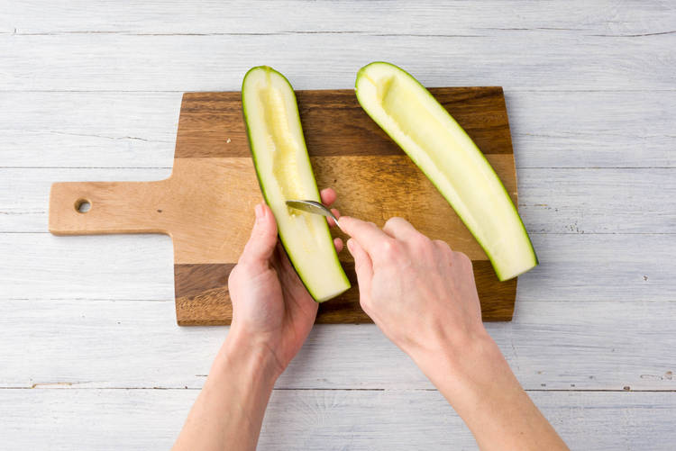 Schraap met een theelepel de kern met de zaden uit de courgette.