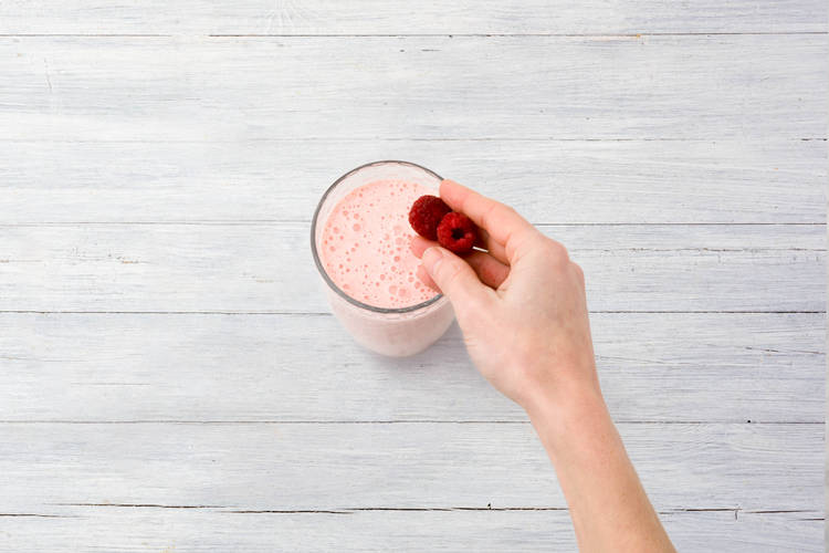 Schenk de smoothie in grote glazen, garneer met de overige frambozen.