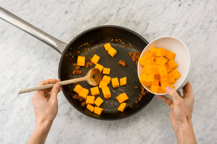 Fruit de rode currypasta en voeg vervolgens de pompoen toe.