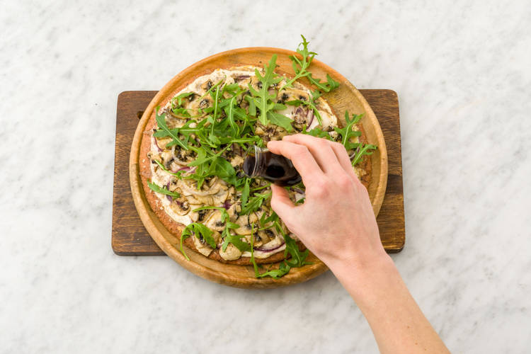 Bestrooi met rucola en besprenkel met zwarte balsamicoazijn.